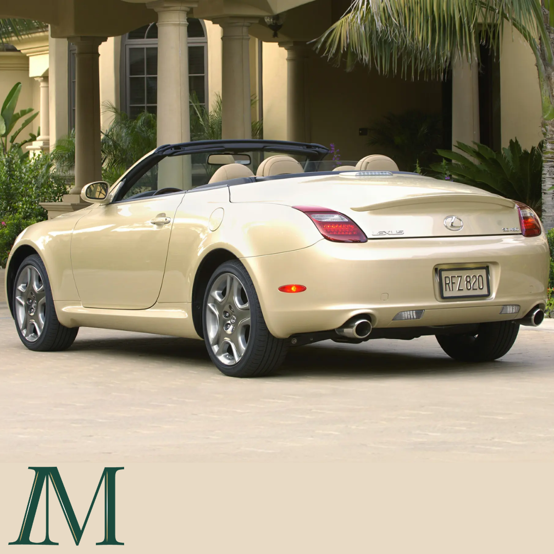 A tan Lexus LS convertible is shown from behind, against a backdrop of stone pillars and palm trees.